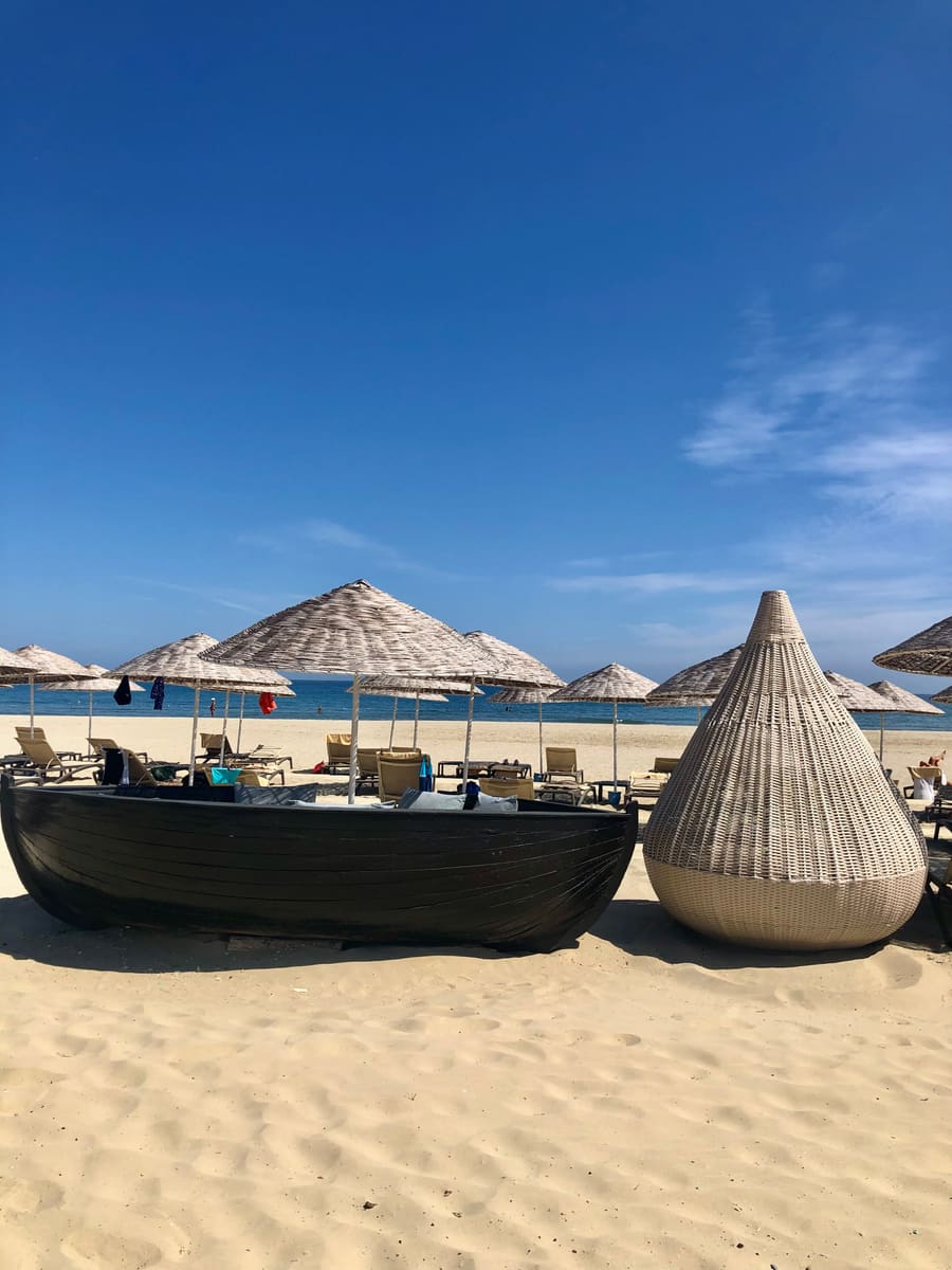 Playa con sombrillas de paja y cabañas de mimbre